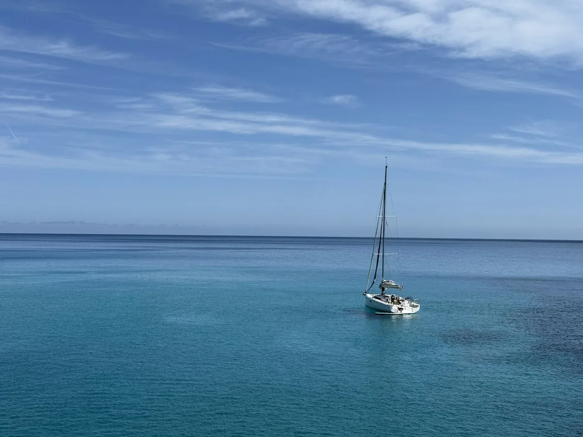 A sailboat floats on crystal clear ocean waters